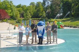 Die Freibadsaison in Witten ist eröffnet. Verantwortliche von Stadtwerken und der Firma SnL Events feiern das Ereignis mit Wasserfontänen.